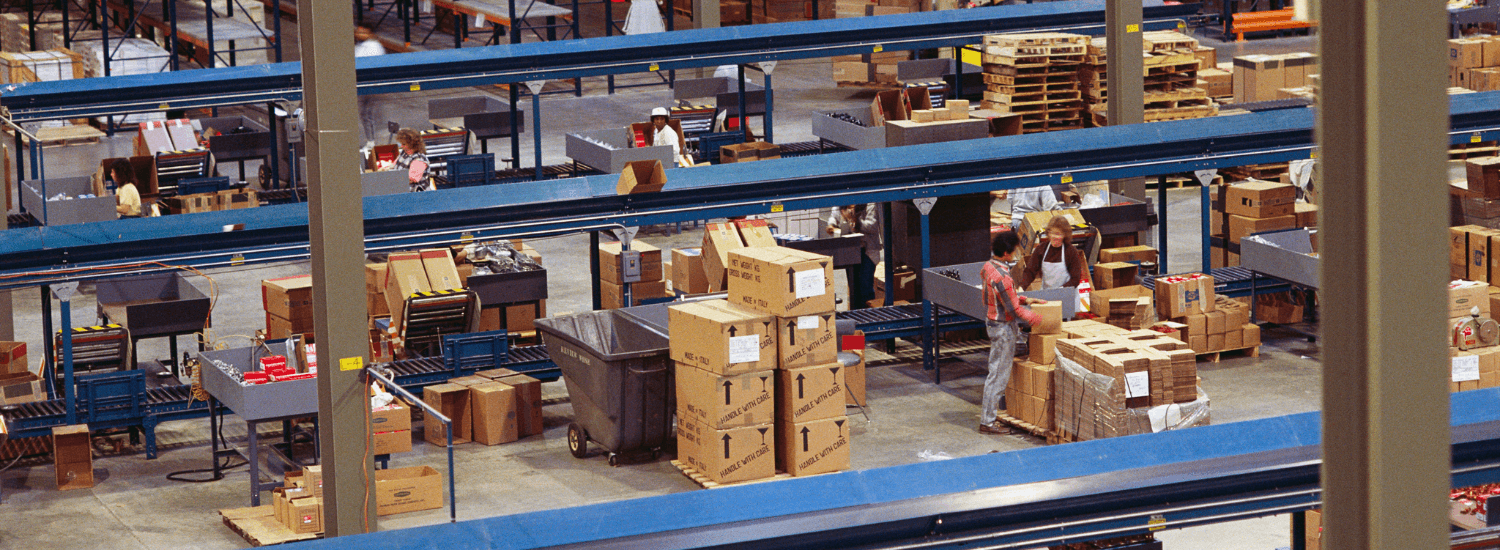 Workers processing boxes on conveyor belt in distribution warehouse